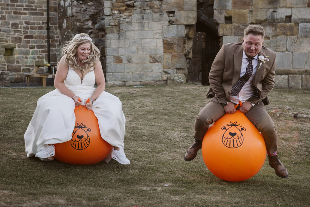 Bride and groom enjoying some space hopper fun during relaxed wedding portraits in North Yorkshire