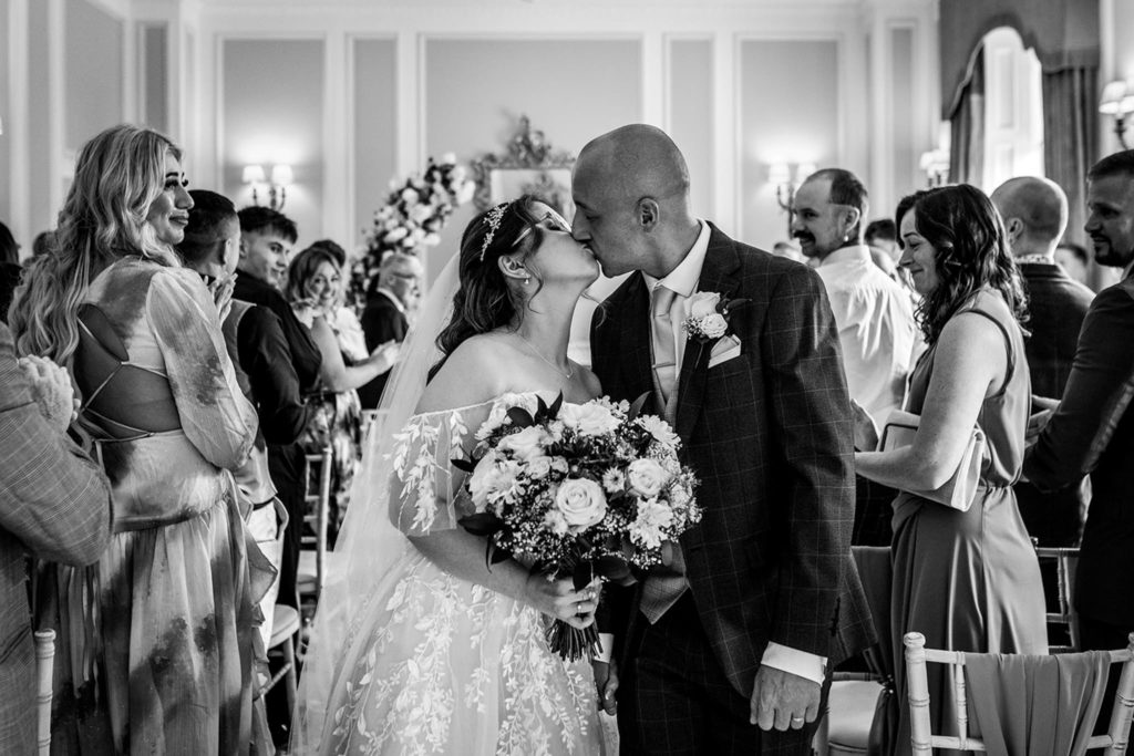 The happy couple sneak a kiss as they leave their ceremony in North Yorkshire