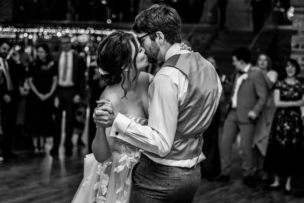 Candid wedding photography capturing the bride and groom kissing on the dancefloor