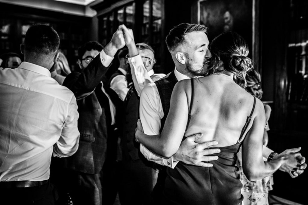 Bride and groom dancing with guests during evening party