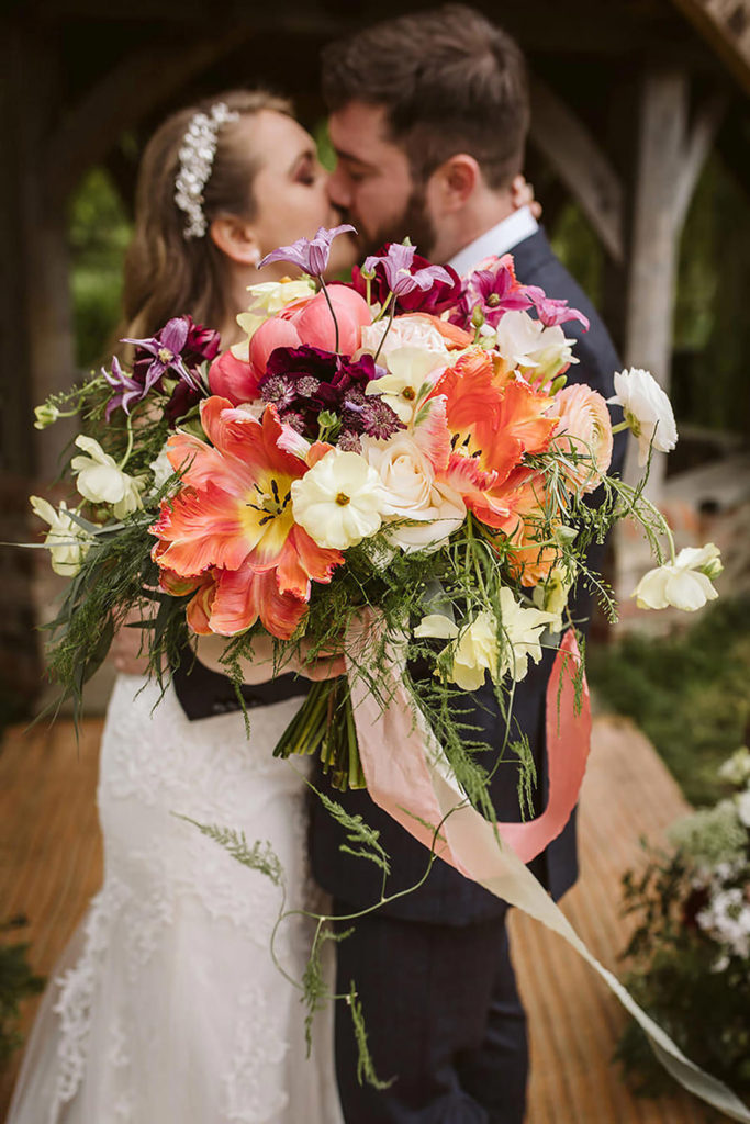 The Bride and Groom share a kiss with the bouquet in the foreground