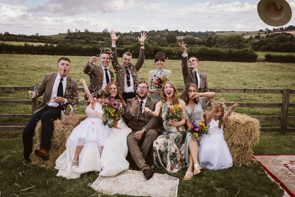 A fun bridal party group shot with confetti and a flying hat