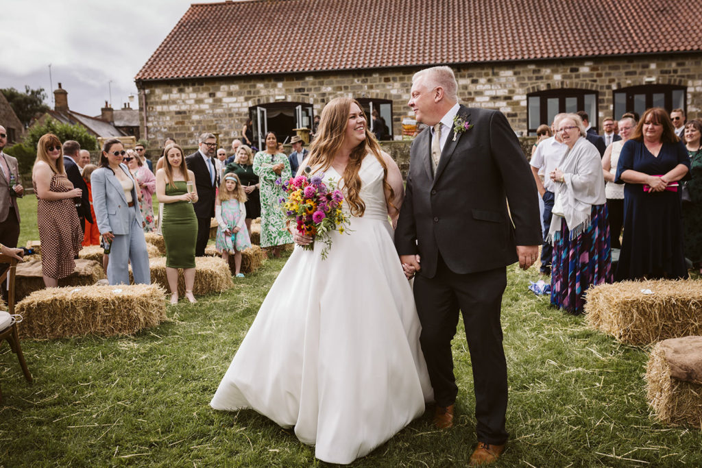 The Bride and her doting Father looking excited as they walk down the aisle