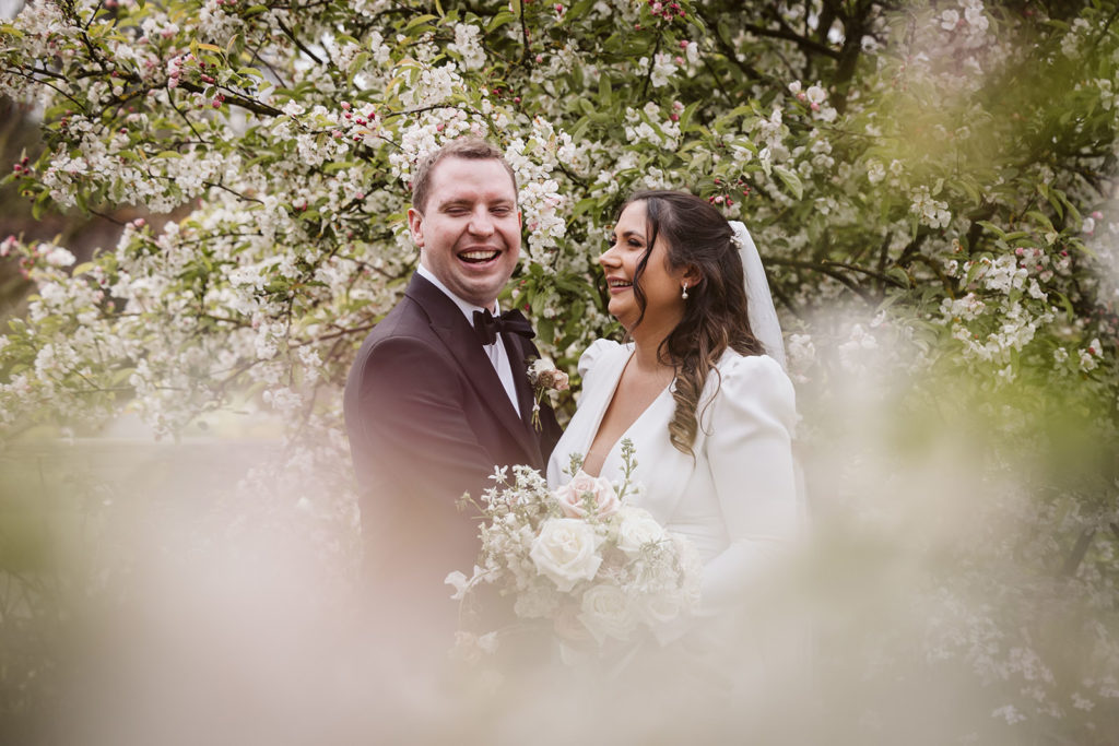 Happy newlyweds nestled among the spring blossom at Middleton Lodge