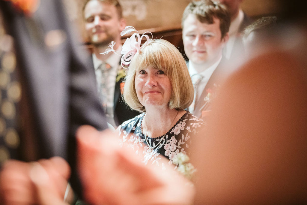 Proud mother of the groom looks on as the couple say their vows