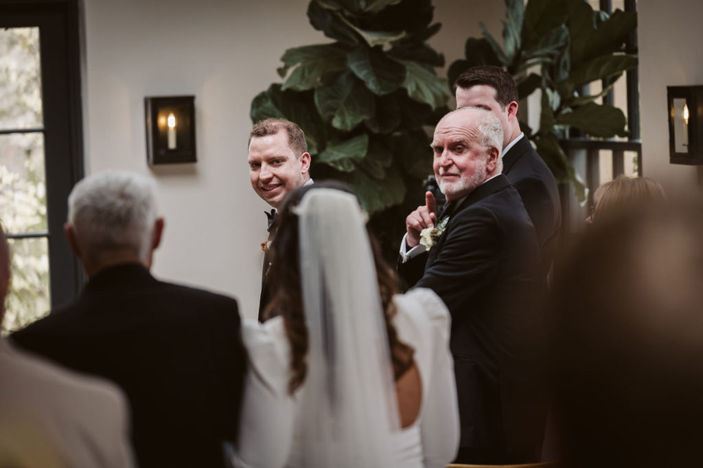 The groom looking back at his Bride and her father arriving at the Fig House, Middleton Lodge.