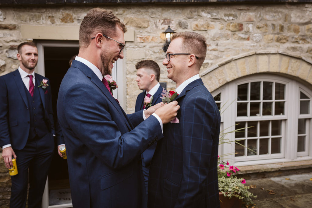 The Best man fitting a buttonhole on the groom
