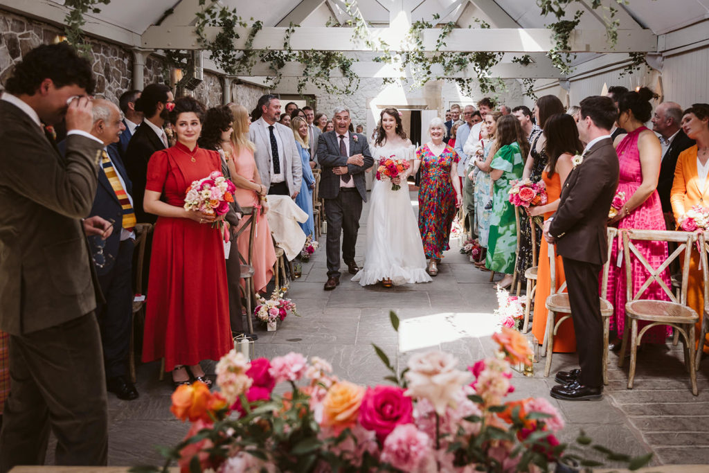 Excited faces as the bride walks down the aisle with both parents