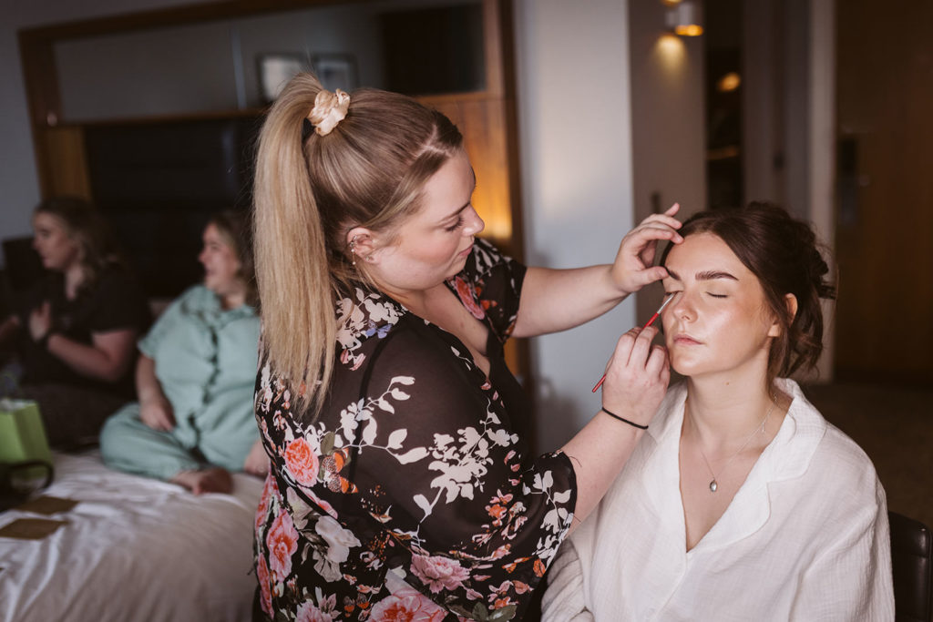 Bridal make up as the bridesmaids chat in the background