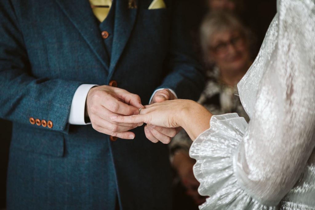 The groom places the wedding ring on his bride