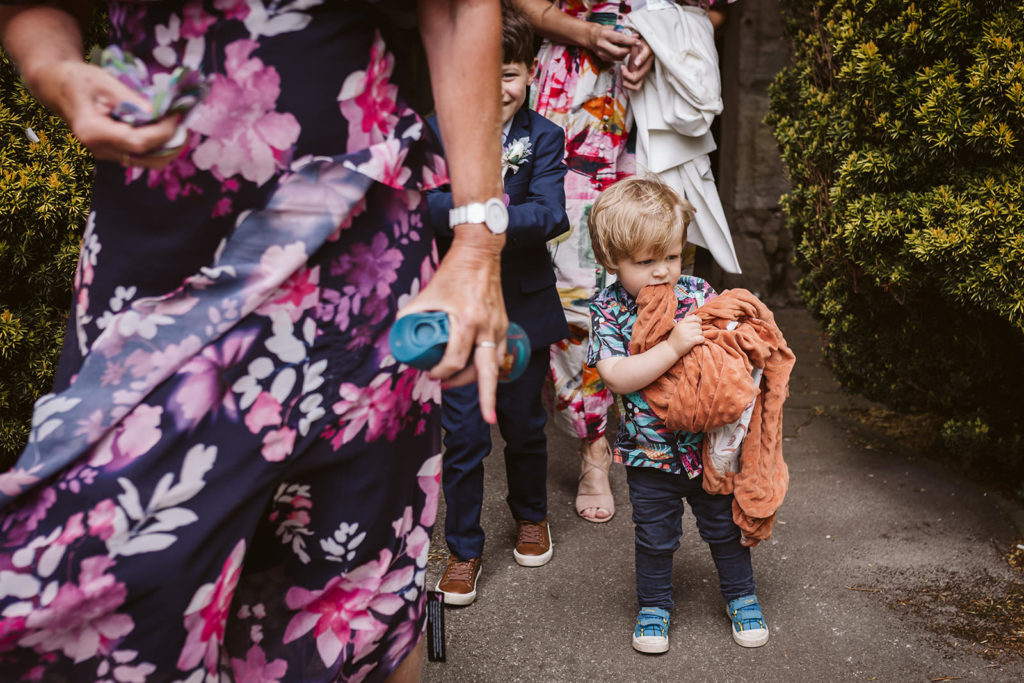 Small wedding guest exits the ceremony with his snuggly