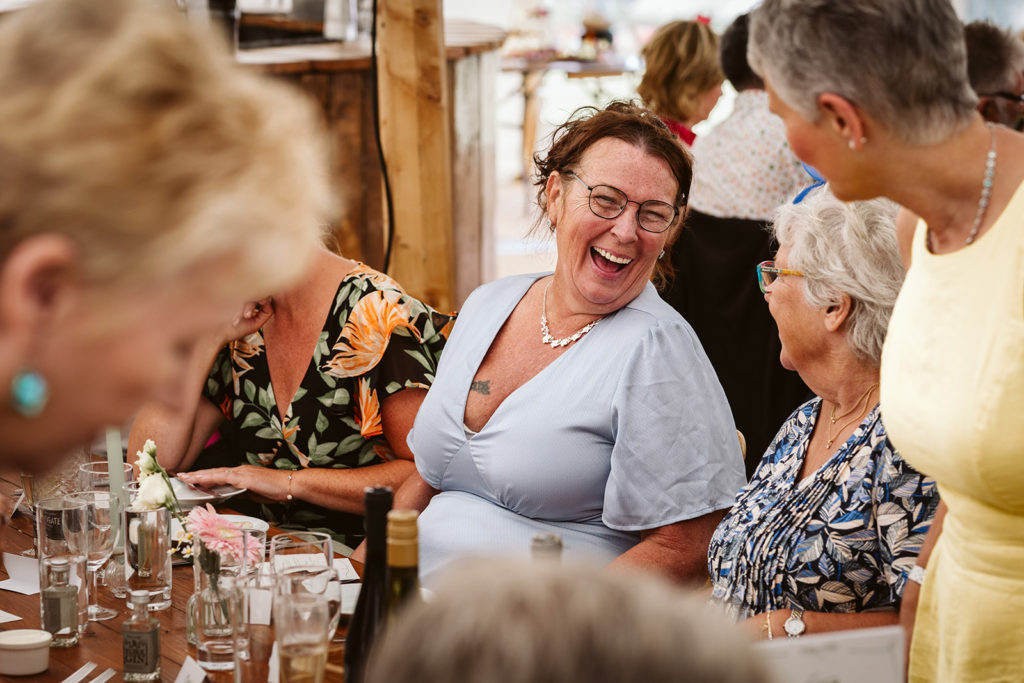 Candid wedding photography of guests laughing during Newburgh Priory marquee wedding