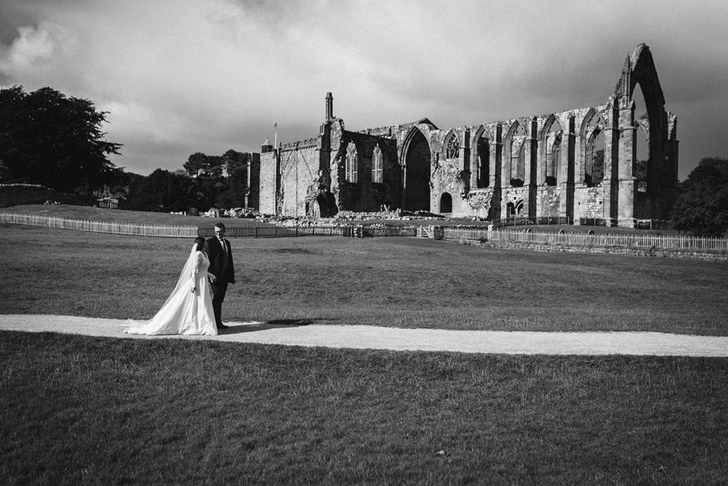 Couple walking by Bolton Abbey during wedding portraits
