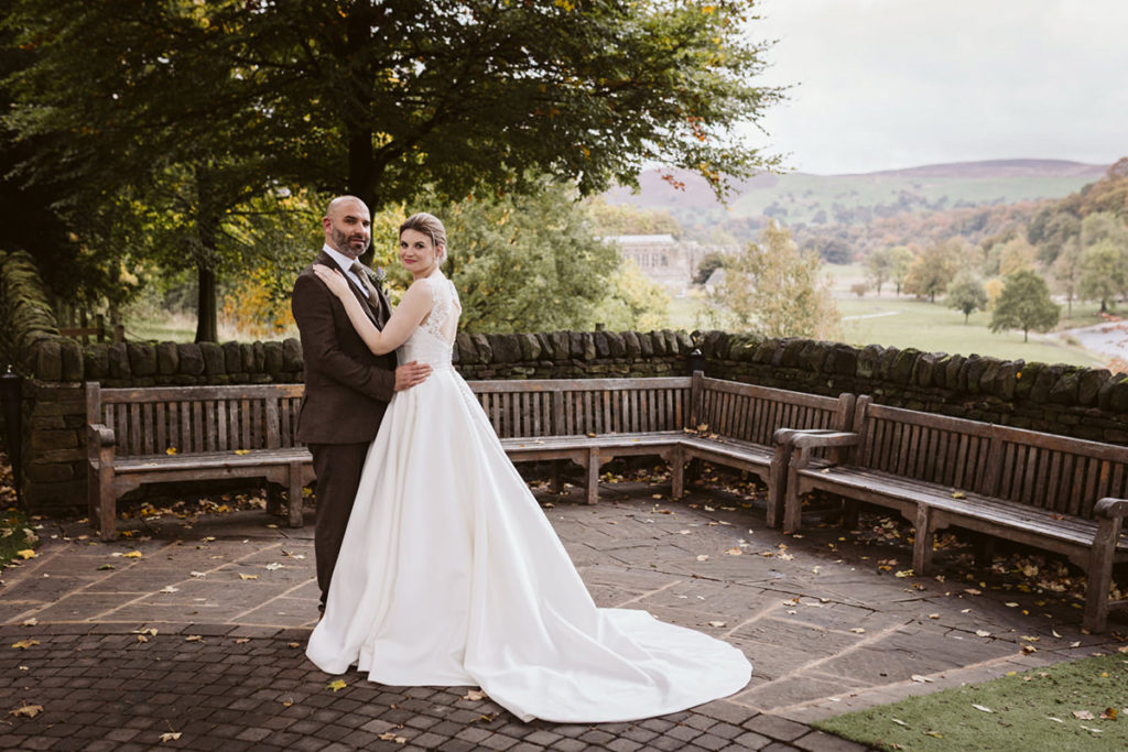 The newlyweds pose for a photo at the Tithe Barn with Bolton Abbey in the background