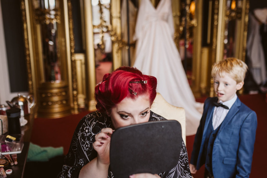The Bride touches up her make up as a young guest looks on