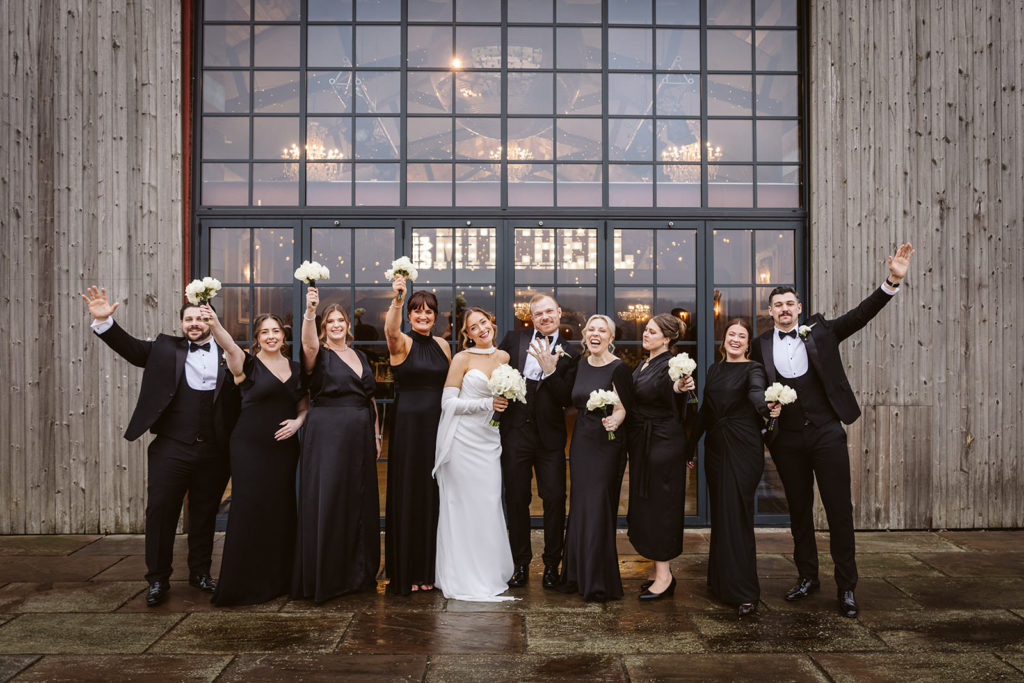 The Bridal party celebrate outside the barn doors of Wharfedale Grange