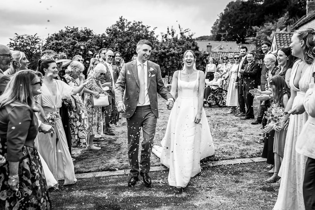 Newlyweds walking through confetti after their wedding ceremony