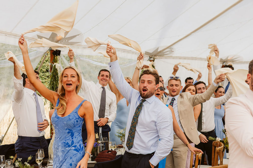 Wedding guests welcome in the happy couple to their marquee wedding
