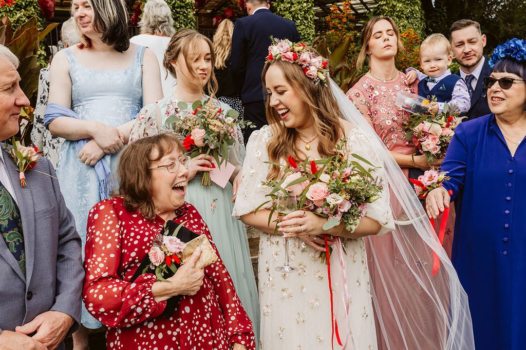 Couple and their families laughing together during a wedding group photograph


