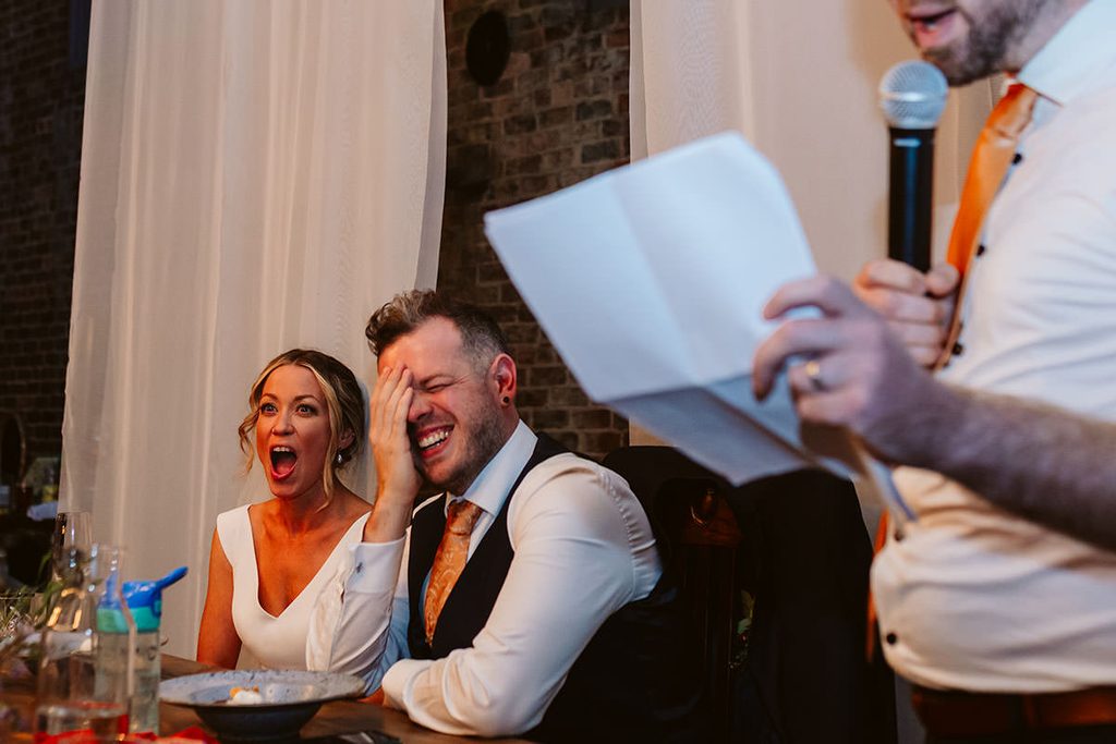 Couple laughing at a speech during their wedding reception

