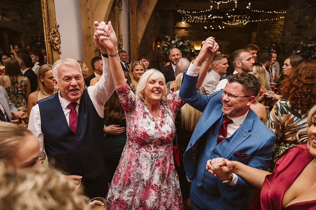 Wedding guests dancing with their arms in the air around the newlyweds