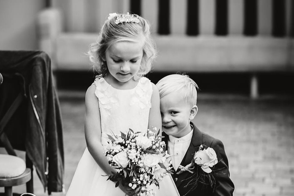 A black and white shot of the happy couple's young children walking down the aisle